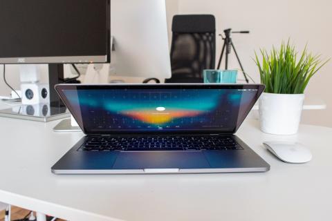 MacBook Pro turned on beside Apple Magic Mouse on top of white surface