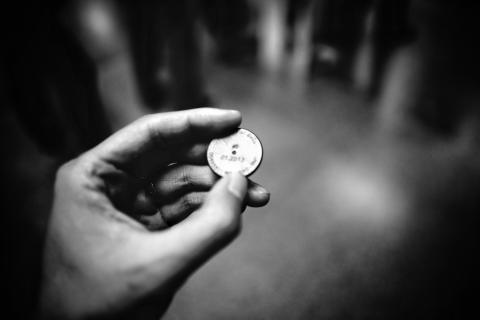 grayscale photography of person holding coin or token