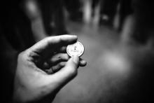 grayscale photography of person holding coin or token